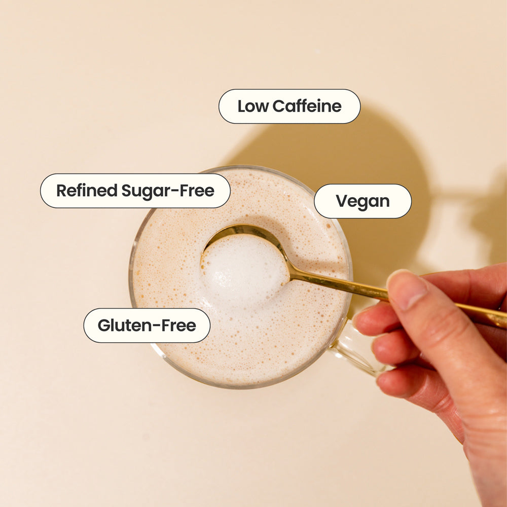 Glass of a beverage with a spoon, labeled as low caffeine, refined sugar-free, vegan, and gluten-free on a beige background.