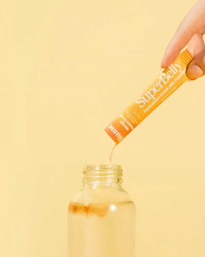 SuperBelly Mango Passionfruit drink mix single packet being added to a bottle of water