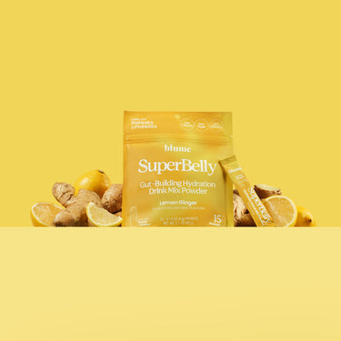 Lemon Ginger Superbelly Drink Mix Package with fresh ginger and lemon slices on a yellow backdrop