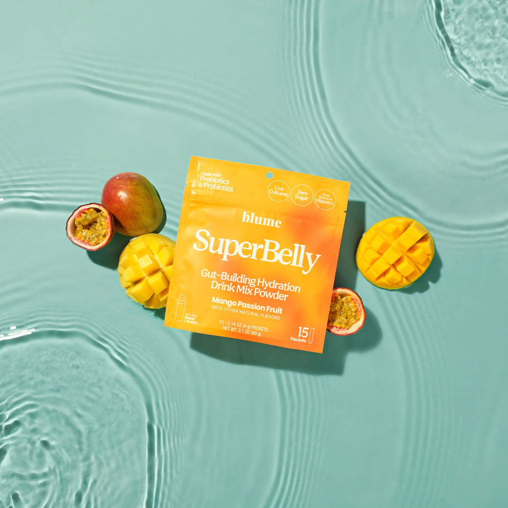 A pack of SuperBelly Mango Passion Fruit in a pool of water with fresh cut mangoes and fresh cut passionfruit