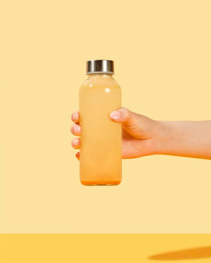 Mango Passionfruit Superbelly Drink being mixed and shaken in a clear water bottle with metal lid