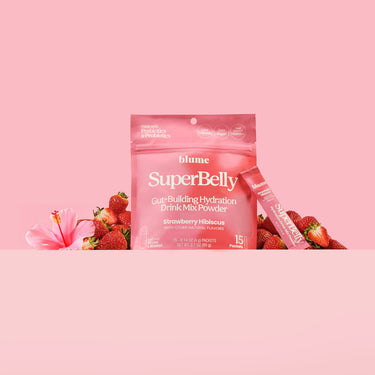SuperBelly Strawberry Hibiscus Gut Health Drink Mix Powder Package with hibiscus flowers and fresh strawberries on a pink background