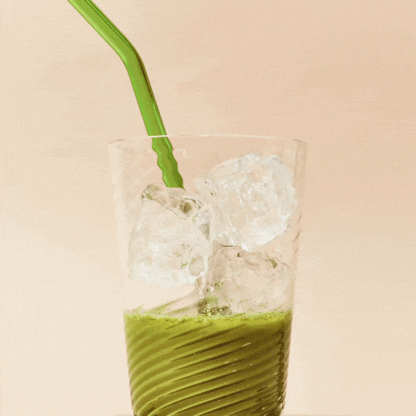 A gif of milk pouring into a glass of matcha latte made with Blume Matcha Coconut Blend on a beige background