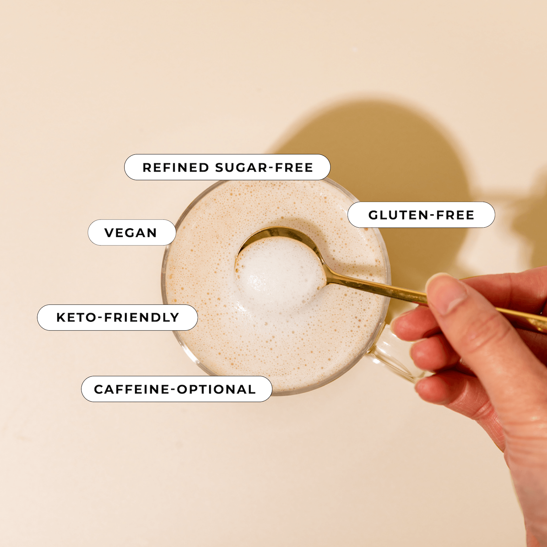 A hand stirs a cup of frothy coffee with Blumes Salted Caramel Blend. Labels above highlight its refined sugar-free, gluten-free, vegan, keto-friendly, and caffeine-optional against a neutral beige backdrop.