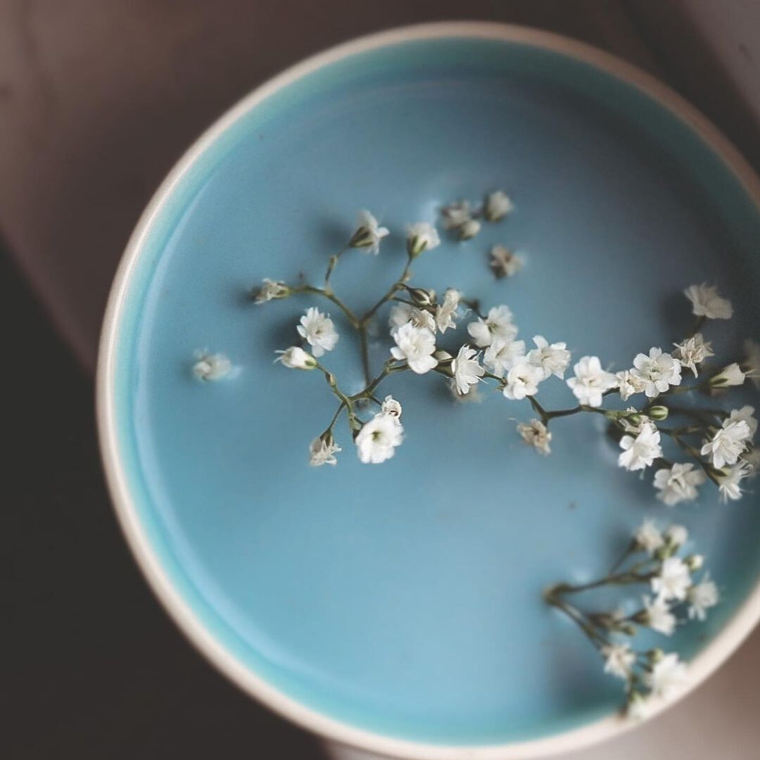 A blue latte made with Blume Blue Lavender Blend with flowers in a cup taken by @anniemgoldade