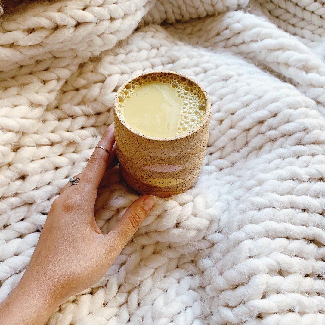 Turmeric latte made with Blume Turmeric Blend on a blanket taken by @gabrielleassaf