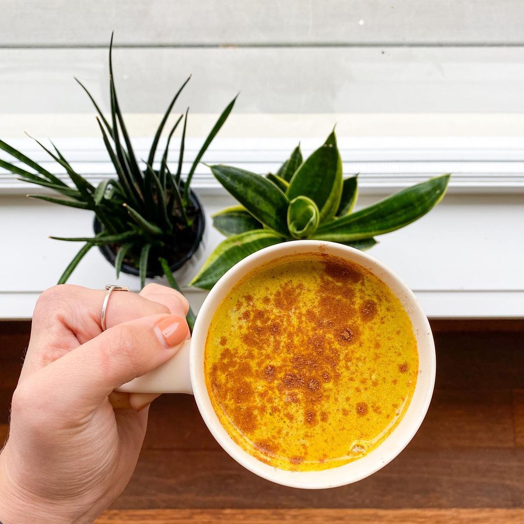 Holding a mug of Blume's Turmeric latte taken by @sweetly_nourished