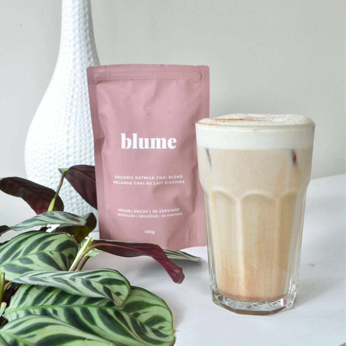 A glass cup of iced chai latte with a bag of Oat Milk Chai Blend taken by @wholesome_hearty_eats